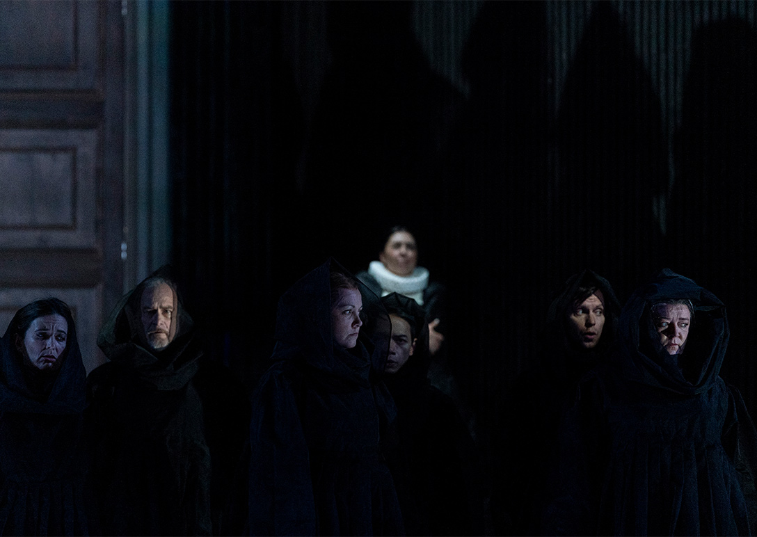 Scene from Maria Stuarda; chorus members in black robes