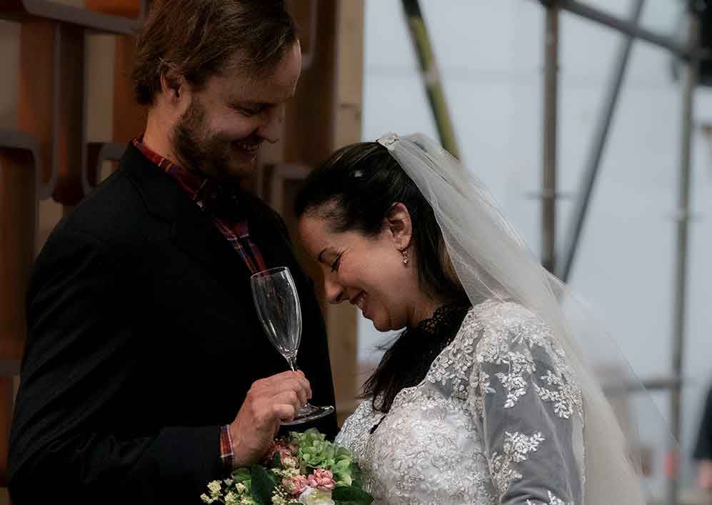 Het gelukkige bruidspaar met champagne en bloemen 