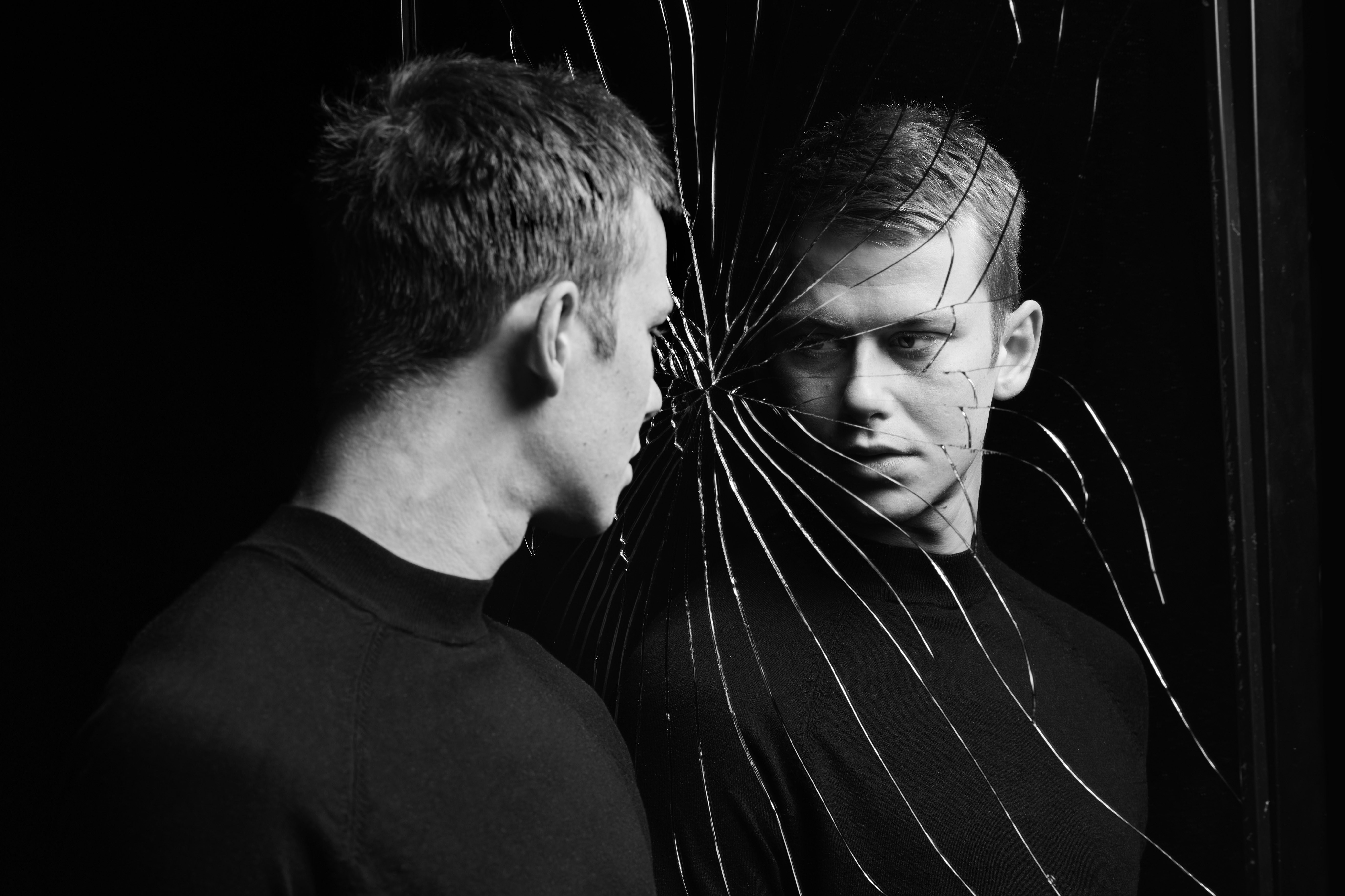 Publiciteitsfoto van Dorian; zwart-witfoto van een jonge man die naar zichzelf kijkt in een gebroken spiegel