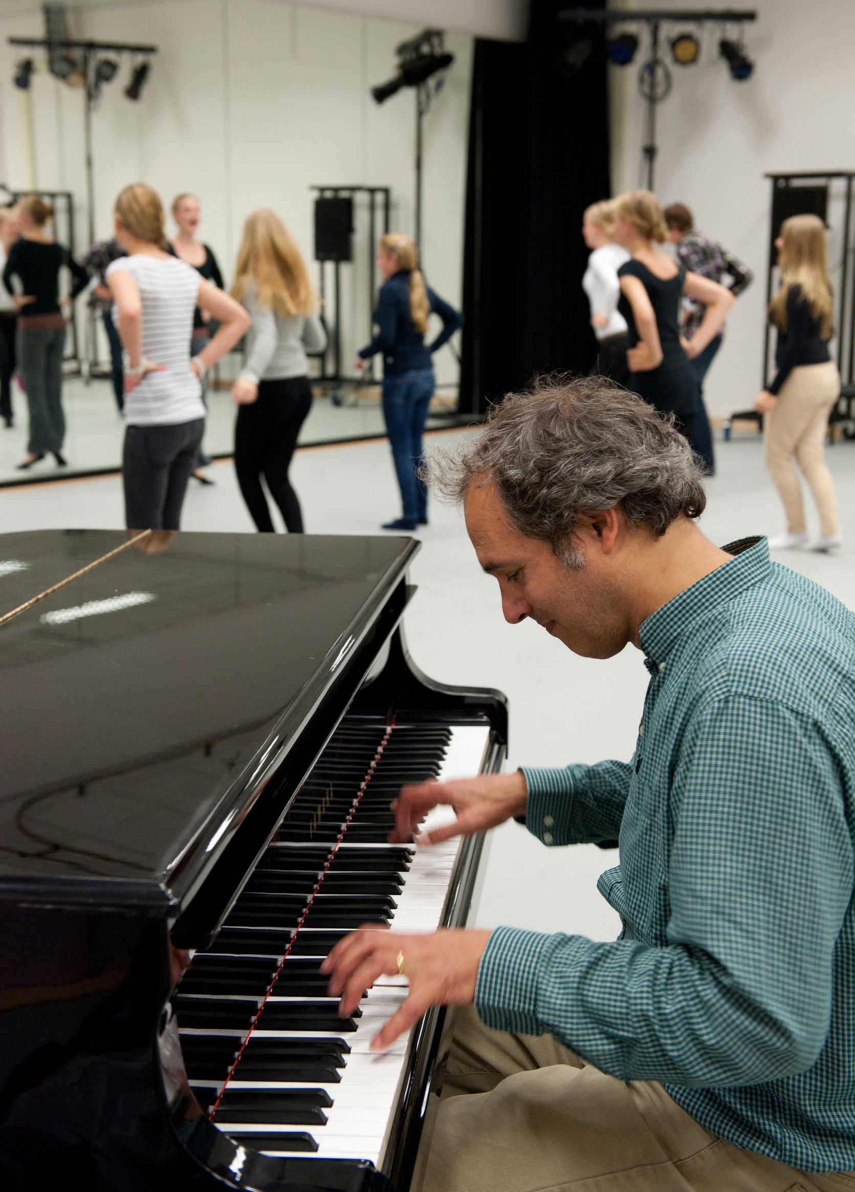 Een pianist speelt terwijl op de achtergrond leerlingen voor een spiegel dansen