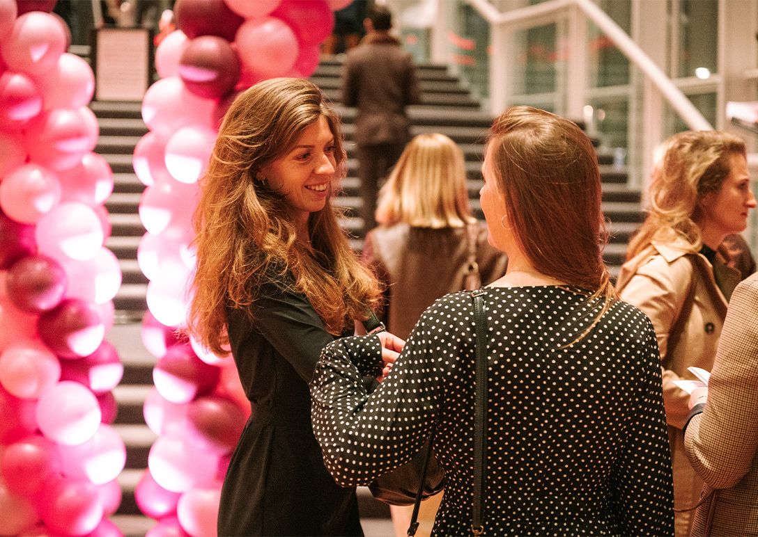 Twee vrouwen kletsen voor de trappen in de foyer