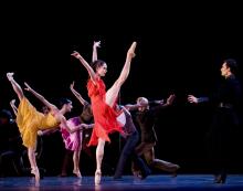 Scènefoto uit de choreografie Carmen van Ted Brandsen. Carmen danst in een rode jurk tegen een zwarte achtergrond