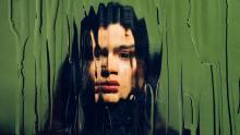 Woman behind glass with raindrops or tears?
