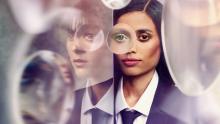 Vrouw met links een spiegelbeeld en glazen van vergrootglazen met haar reflectie