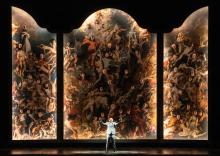 Gevorg Hakobyan (Il barone Scarpia) in front of a grand triptych with singers from the Chorus of Dutch National Opera.