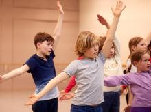 Kinderen staan in danspose in een repetitieruimte